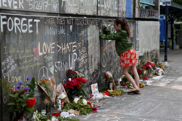 Image: A girl leaves a message at a makeshift memorial for two men who were killed on a commuter train while trying to stop another man from harassing two young women who appeared to be Muslim, in Portland