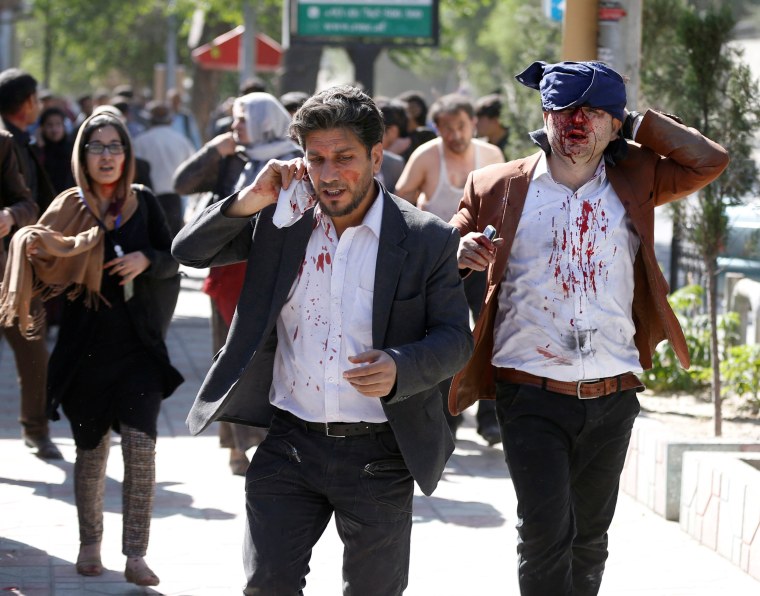 Image: Injured Afghans run from the site of a blast in Kabul, Afghanistan