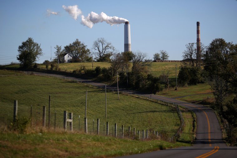 Image: A county road winds through farmland as emissions rise from a generating station