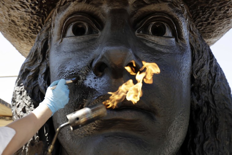 Image: Eliot Bassett-Cann, with Moorland Studios Inc., applies a protective coating to the sculpture of William Penn atop City Hall