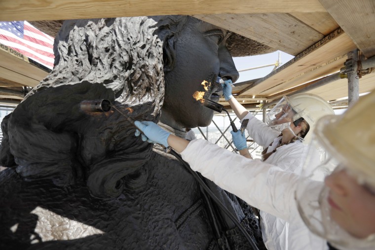 Image: Eliot Bassett-Cann, left, and Margaret Parrish, with Moorland Studios Inc., apply a protective coating to the sculpture of William Penn