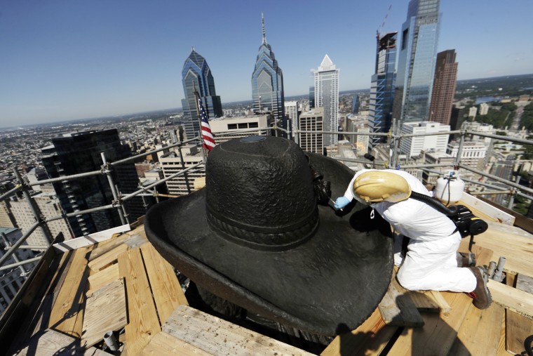 Image: James Bassett-Cann, with Moorland Studios Inc., applies a protective coating to the sculpture of William Penn atop City Hall