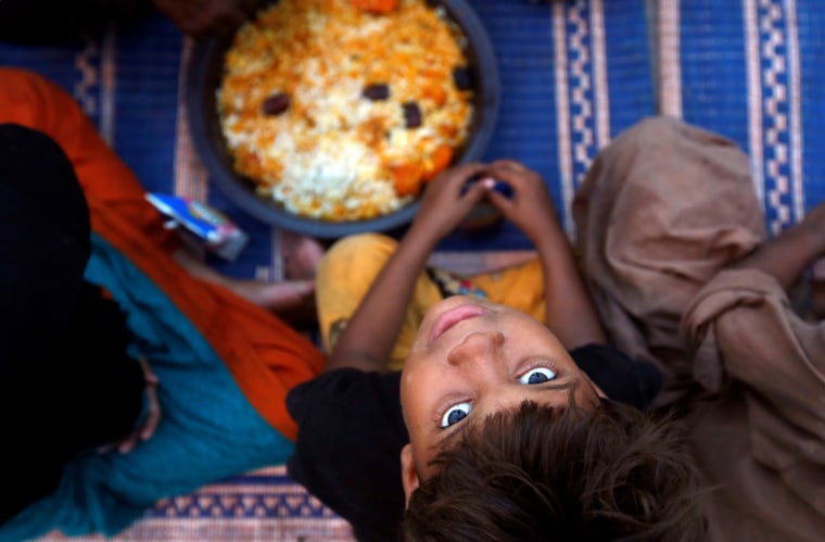 Image: A boy sits with others as they wait to break their fast at a charity food distribution point along a road during a Muslim holy month of Ramadan in Karachi