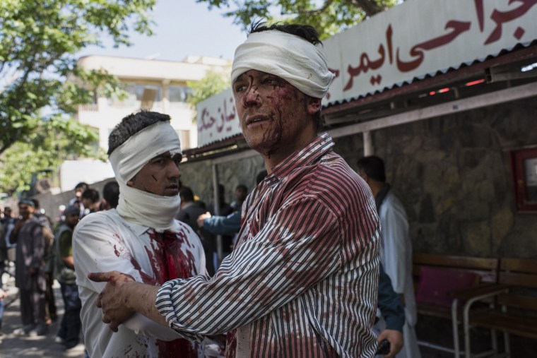 Image: Two injured men leave a hospital after receiving first aid treatment, a few blocks away from where a truck bomb exploded in central Kabul, Afghanistan.