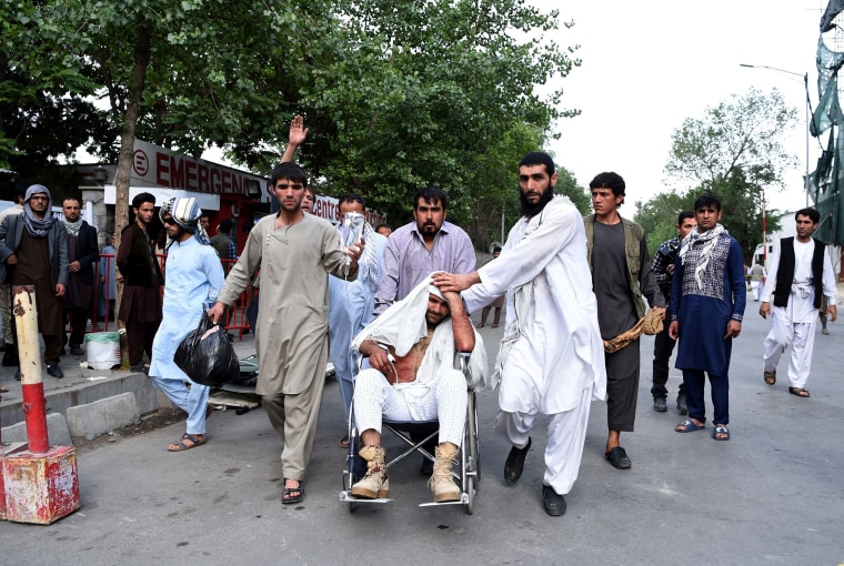 Image: Afghan relatives push the wheelchair of a wounded man outside an Italian aid organization's hospital following the series of explosions.