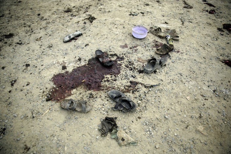 Image: Shoes, a hat, and blood stains mark the spots where funeral attendees were killed or injured.