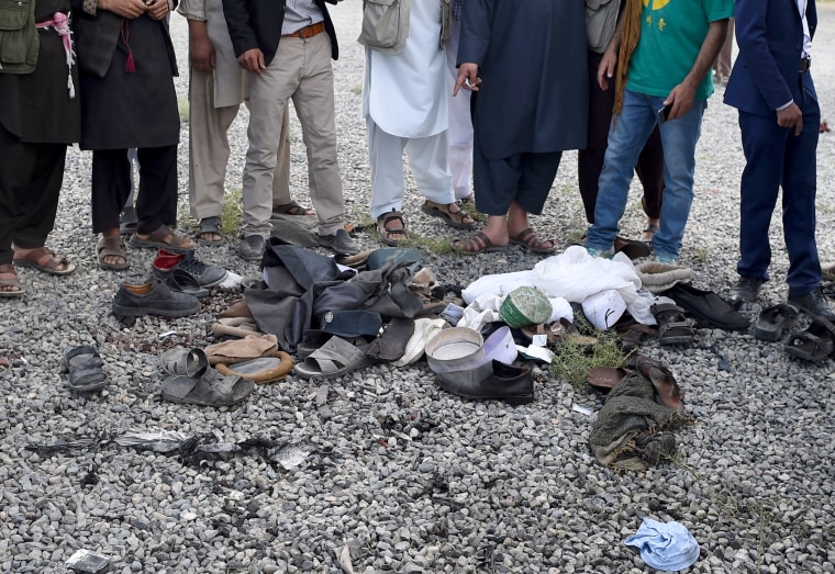 Image: Men look over the belongings of blast victims.