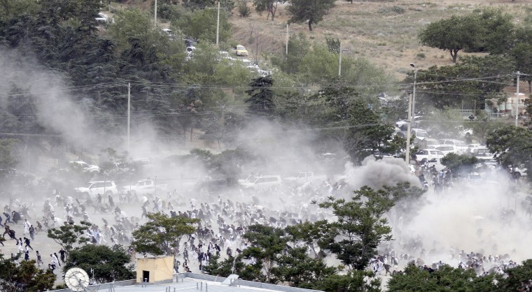 Image: Funeral goers break into a run after one of three suicide bombers detonated during the ceremony.