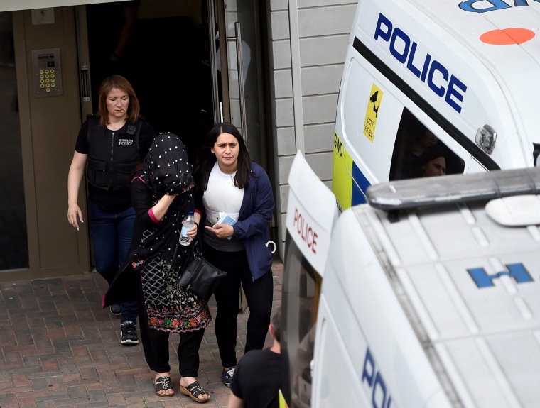 Image: Police officers escort a woman to a police van following a raid in Barking.