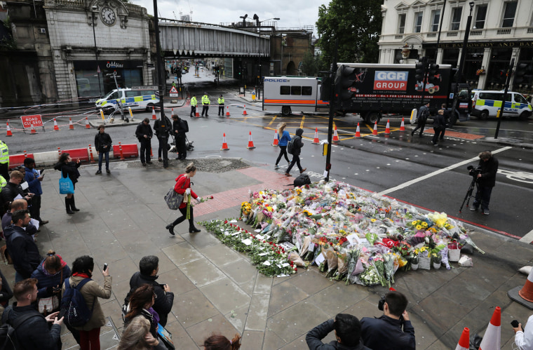 Image: A woman places a rose with other floral tributes for the victims of the attack on London Bridge and Borough Market at London Bridge, London