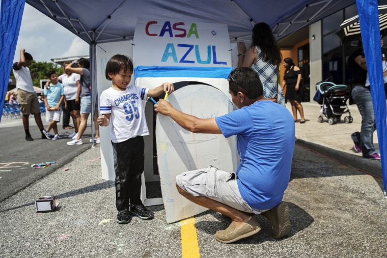 Image: Miguel helps out a boy as he participates in a public art project at a booth