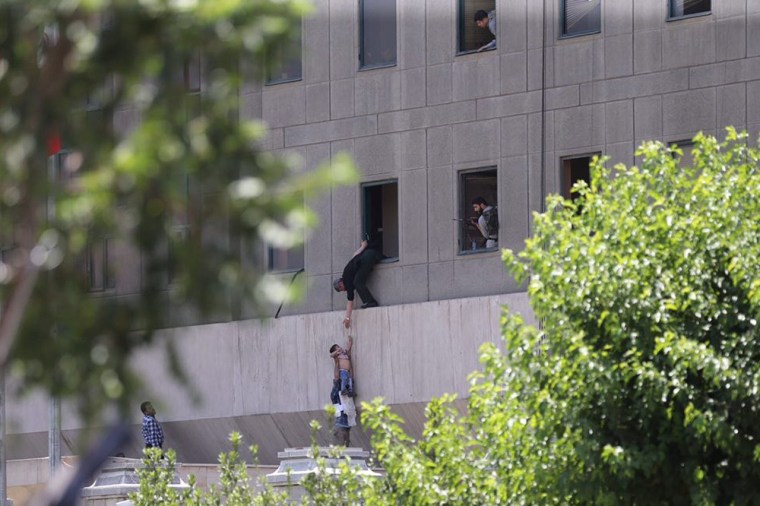 Image: Iranian policemen try to help some civilians fleeing from the parliament building during an attack in Tehran