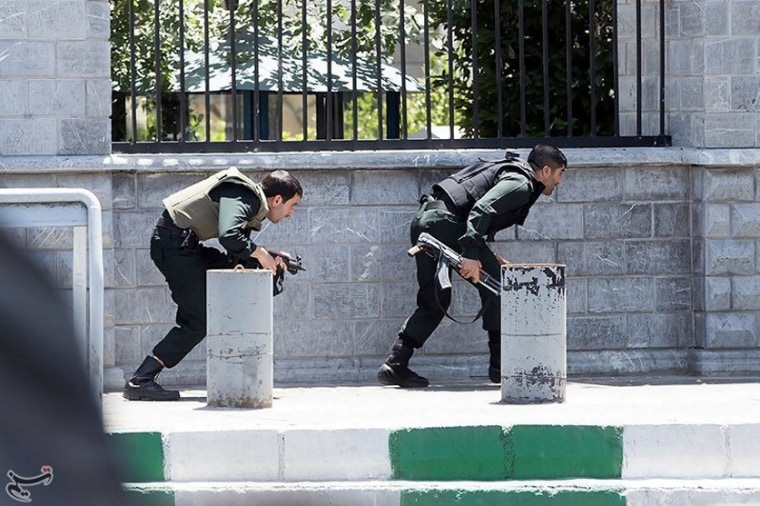Image: Members of Iranian forces take cover during an attack on the Iranian parliament in central Tehran