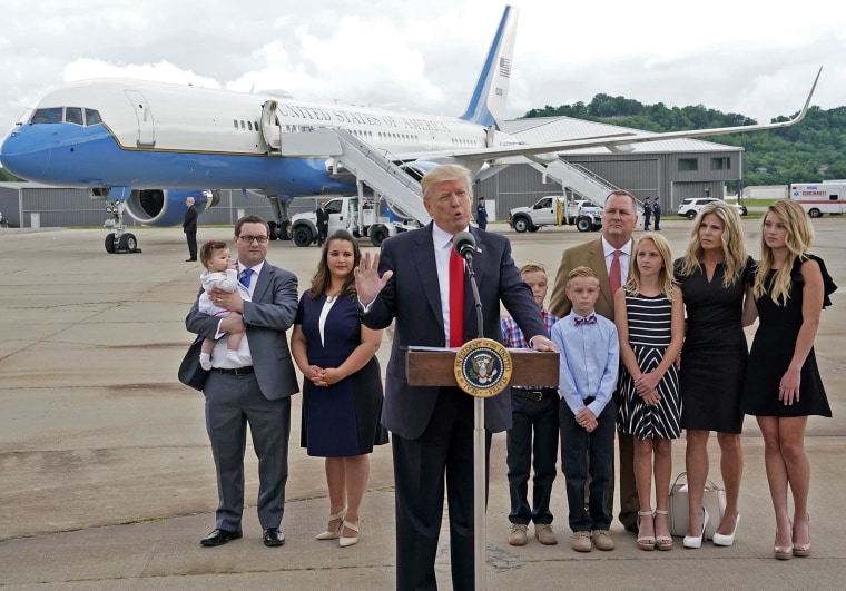 Image: U.S. President Trump stands with families whose insurance premiums rose under the Affordable Care Act after arriving in Cincinnat
