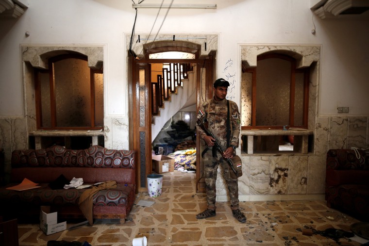 Image: A member of the Iraqi Army's 9th Armoured Division stands inside a compound used as a prison by Islamic State militants