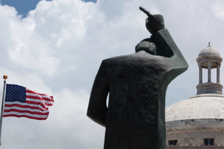 Image: The statue of St. John and the U.S. flag are seen outside the Capitol building in San Juan