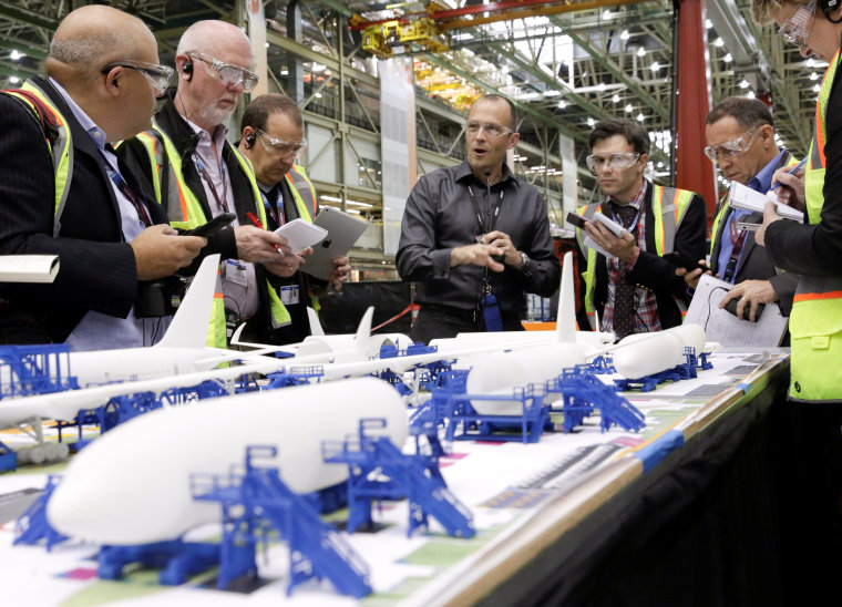 Image: Jason Clark (4th L), Vice President of Boeing 777 and 777X Operations, points to a model during a media tour of the 777 Wing Horizontal Build Line at Boeing's production facility in Everett, Washington