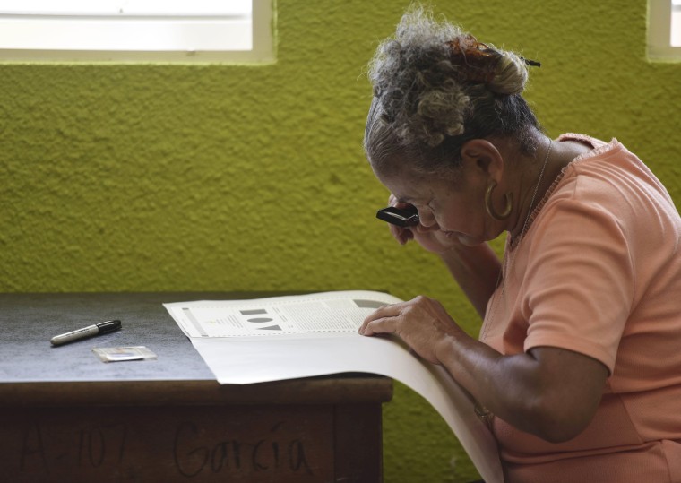 Image: Puerto Rican resident Marla Quinones looks carefully at her ballot