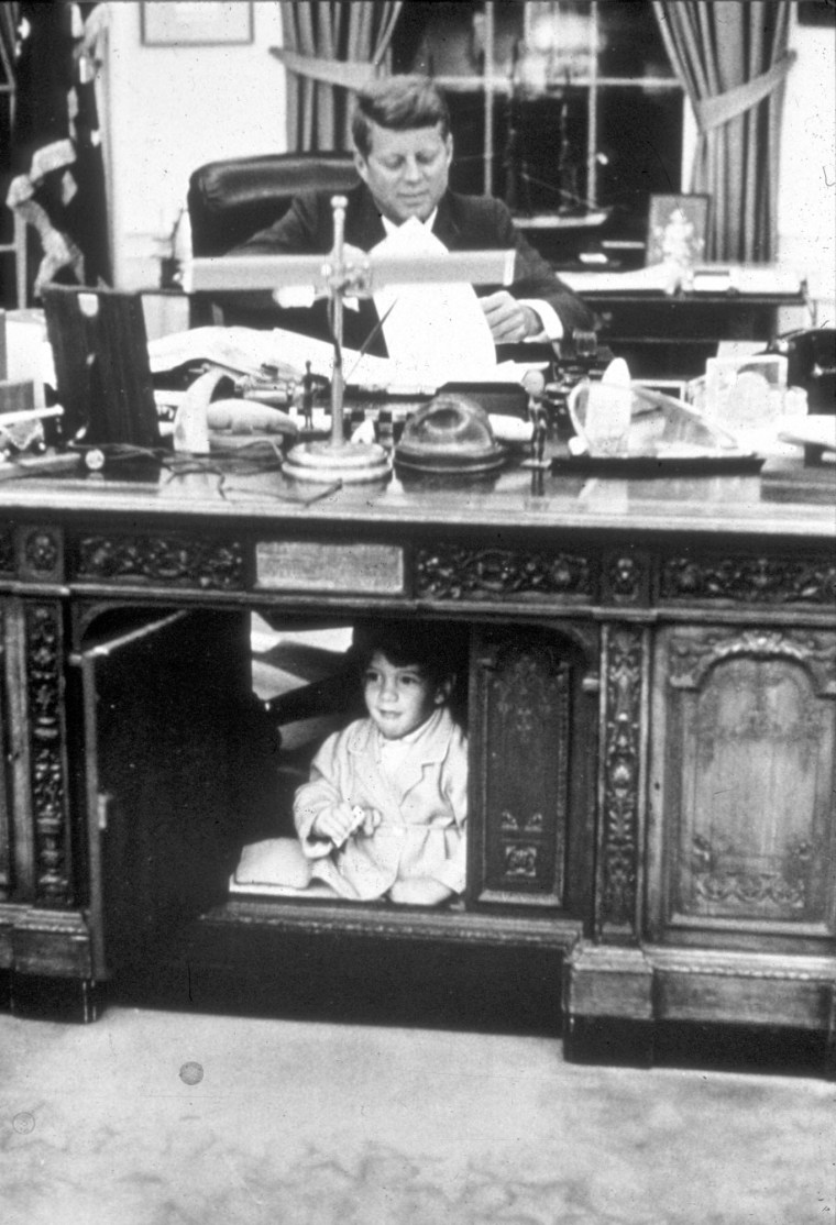 John F. Kennedy Jr. hides in his father's Oval Office desk in October 1963.