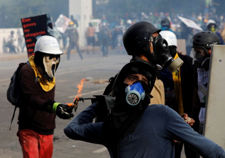 Image: A demonstrator throws a petrol bomb while clashing with riot security forces during a rally against Venezuela's President Nicolas Maduro in Caracas