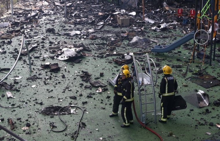 Image: Firefighters stand amid debris in a childrens playground near a tower block severly damaged by a serious fire, in north Kensington, West London