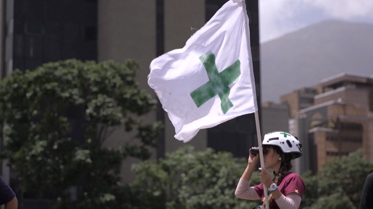 A Green Helmets volunteer keeps watch during clashes between protesters and security forces in Caracas, Venezuela.