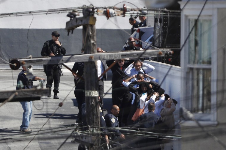 Image: People being evacuated hold their hands above their heads after a shooting incident at a UPS facility in San Francisco