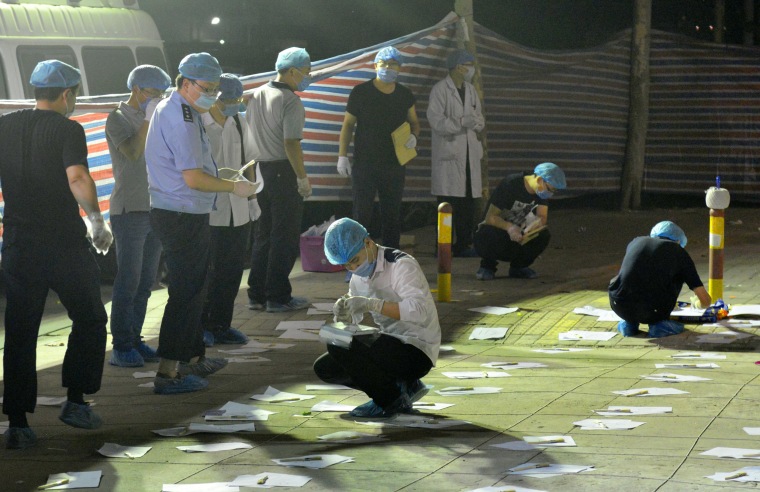 Image: Police officers examine the entrance to a kindergarten, where an explosion killed at least eight people, in Xuzhou, China