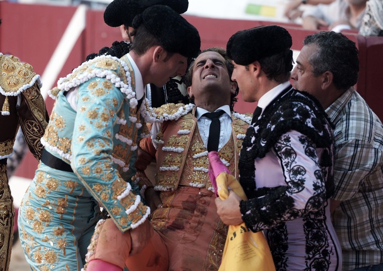 Image: Spanish matador Ivan Fandino, center, is assisted after being impaled by a Baltasar Iban bull during a bullfight