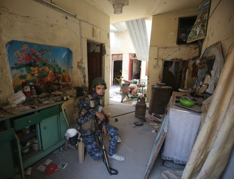 Image: A member of the Iraqi forces rests inside a house