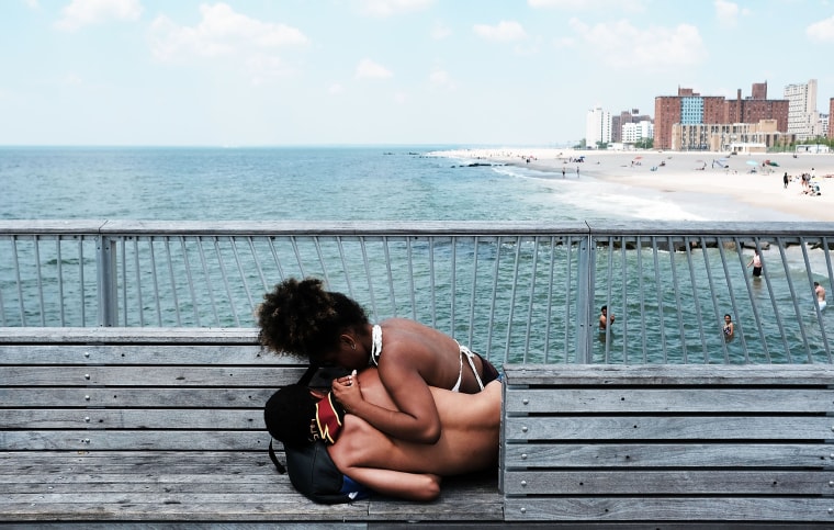 Image: Teenagers relax along the boardwalk on a hot day at Coney Island as sweltering summer temperatures grip New York City