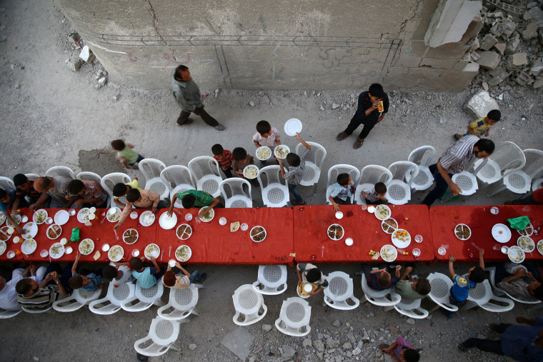 Image: People break their fast amidst damaged buildings during an Iftar in the rebel held besieged Douma neighbourhood of Damascus