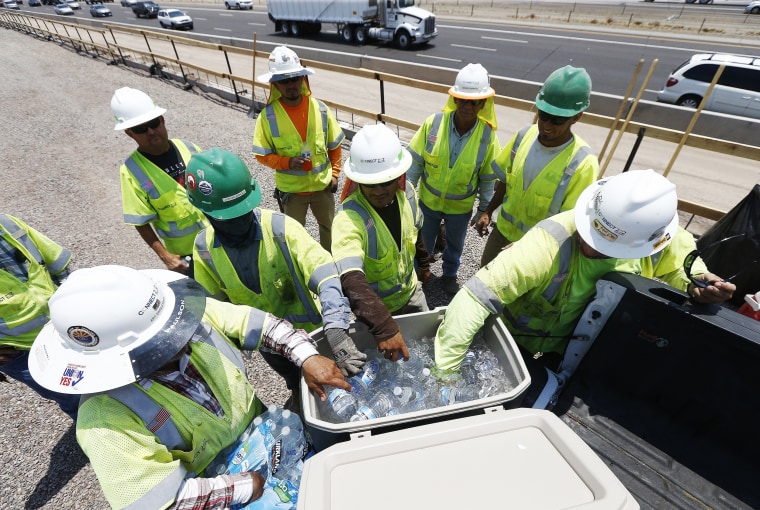 Image: Crew members building the Loop 202 South Mountain Freeway take a break as they try to keep hydrated and stay cool