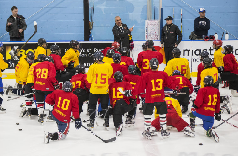 Players kneel on the ice as they listen to a coach during a training camp hosted by China's national hockey team.