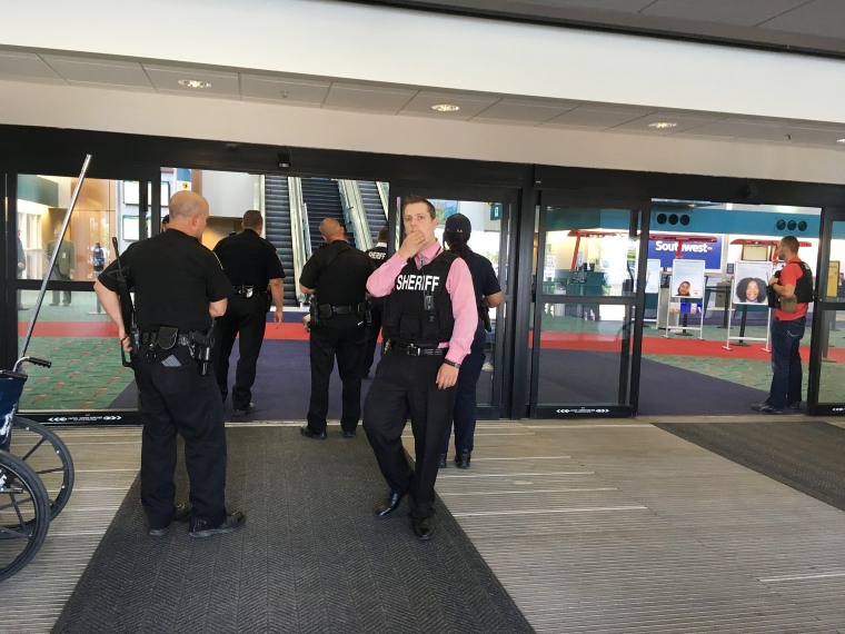 Image: Police officers gather at a terminal at Bishop International Airport