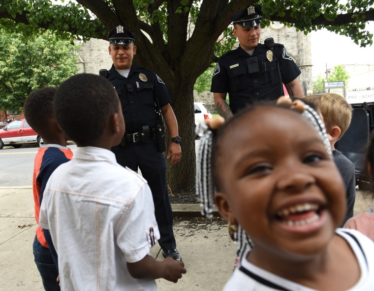 Image: A schoolgirl smiles as Camden County Police Department officers are seen on foot patrol in Camden