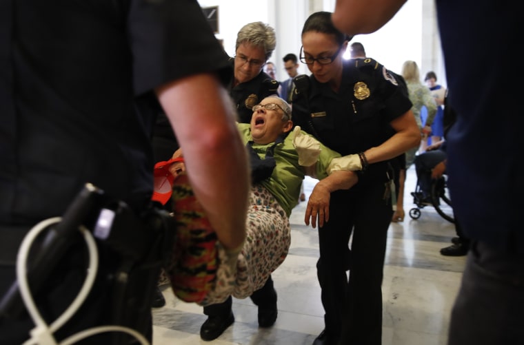 Image: A woman is removed from a sit-in outside of Senate Majority Leader Mitch McConnell's office