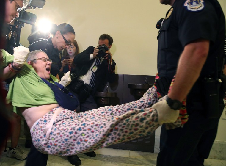 Image: U.S. Capitol Police remove a woman from a protest in front of the office of Senate Majority Leader Mitch McConnell