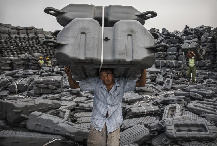 Image: A Chinese worker carries flotation devices for a solar project