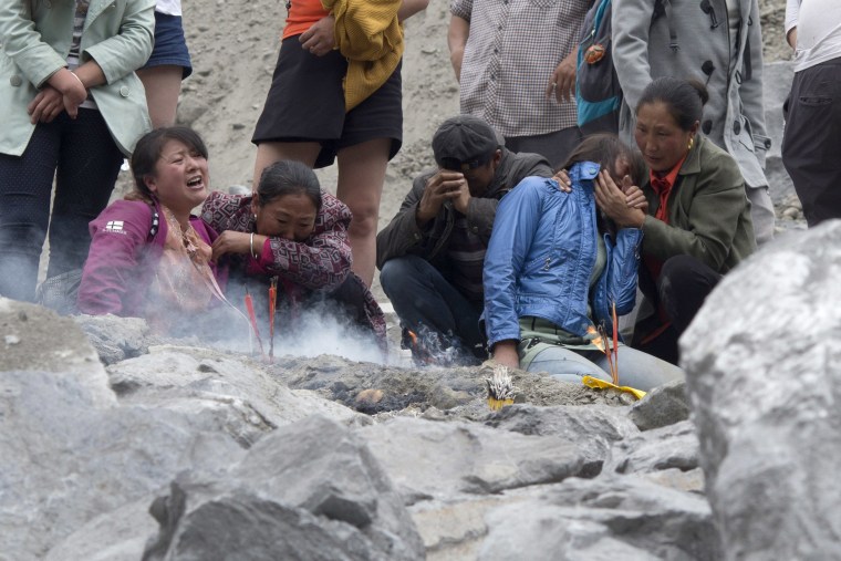 Image:  Mourners wait at the site of the landslide while rescue workers clear rubble in search of bodies on June 25.