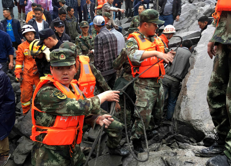 Image: Chinese military police and rescue workers look for victims on June 25.