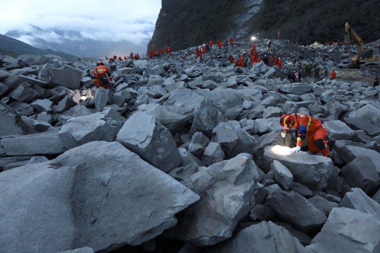 Image: Rescue workers search for survivors into the night on June 24.