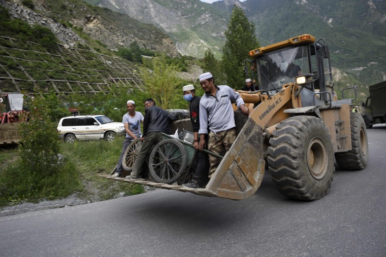 Image: A group of Chinese Muslims stand on an excavator after bringing food to rescuers on June 24.