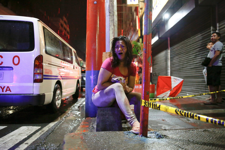 Image: A woman cries after her husband was shot dead by unidentified gunmen riding motorcycles in Manila