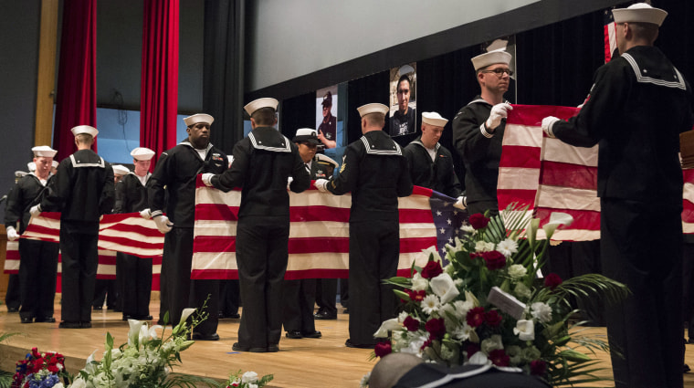 Image: Sailors fold seven U.S. flags during a memorial ceremony