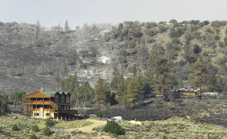 Image: A home that was saved, left, stands next to one that burned to the ground during the "Brian Head Fire" wildfire above Panguitch Lake