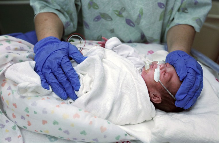 Image: neonatal outcomes nurse swaddles preemie baby