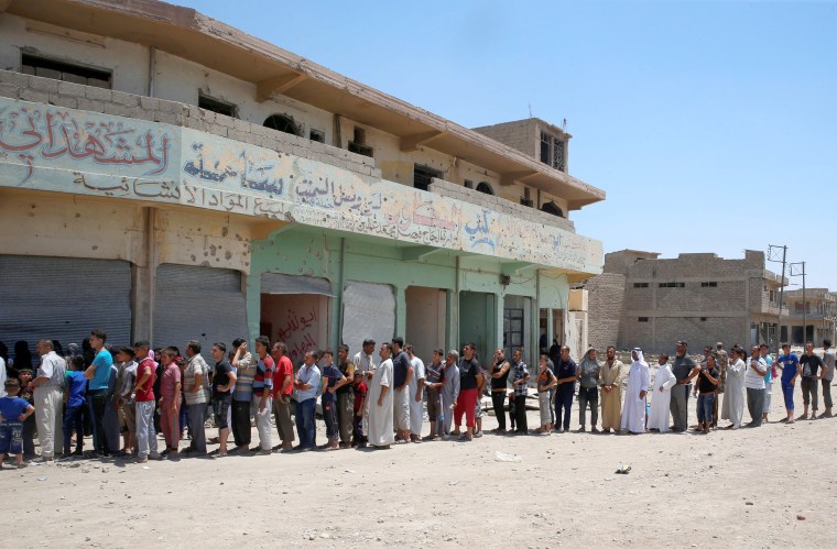 Image: Displaced Iraqi residents queue as they wait for the food distribution by an aid organization during the first day of Eid-al Fitr celebration in West Mosul, June 25.