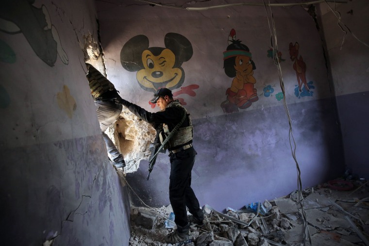 Image: Iraqi forces climb through a hole in the wall as they advance through the Old City of Mosul on June 25, during the ongoing offensive to retake the last district held by the Islamic State.
