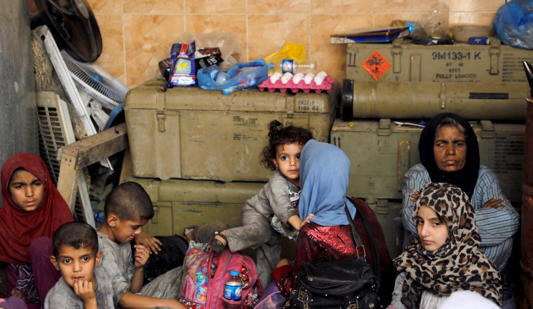 Image: Displaced Iraqi civilians who were rescued from the site of a battle rest among Iraqi forces on June 29.